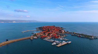 Kırmızı çatıları ve marina tesisleri olan tarihi ada şehri. Marina ve teknelerin yer aldığı bir köprüyle bağlı bir adada bulunan eski bir kasabanın hava görüntüsü..