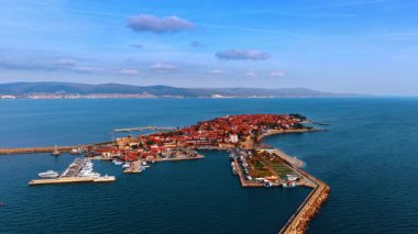 Limanı olan bir yarımadada antik bir kasabanın havadan görünüşü. Liman ve tekneli yarımada üzerinde kırmızı çatıları olan tarihi bir kasabanın yüksek açılı perspektifi.