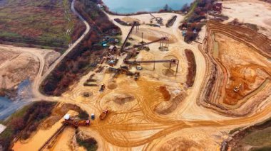 Kum ocağındaki endüstriyel taşıma bantları ve makineler. Yüksek açılı kum işleme ekipmanları, taşıyıcılar, kum yığınları ve bölgede ağır kamyonlar.