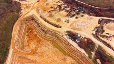 Kumlu taş ocağında kazıcı. Arka planda bir işleme fabrikası olan katmanlı bir kum çukurunda çalışan bir kazıcının hava perspektifi.