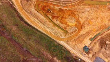 Kum havuzunda çalışan kazıcının yukarıdan görünüşü. Su kanallı turuncu kumda çukur kazan sarı hidrolik kazıcının dikey görüntüsü.