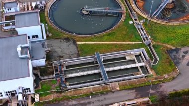Atık su santralindeki ikincil temizleyiciler ve havalandırma havzaları. Su arıtma işlemi sırasında martılarla birlikte dairesel ve dikdörtgen tankların üst görünümü.