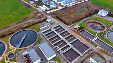 Belediye atık su arıtma tesisi altyapısı. Modern bir kanalizasyon arıtma istasyonunda geniş açılı dairesel netleştiriciler ve dikdörtgen havalandırma tankları gösteriliyor..