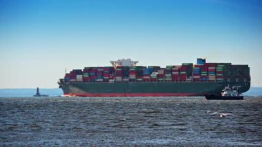 New York, ABD, 5 Ekim 2025: Denizdeki yeşil bir konteynır gemisinin yan görüntüsü. Güvertede renkli konteynırlar ve yakınlarda küçük bir tekne olan büyük bir yük gemisinin profili..