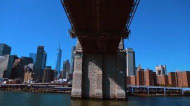 New York, ABD, 5 Ekim 2025: Brooklyn Köprüsü 'nün altından Manhattan ufuk çizgisinin görüntüsü. Bir köprünün taşı ve çeliği ile çerçevelenmiş nehir ve gökdelenlerin alçak açılı görüntüsü.