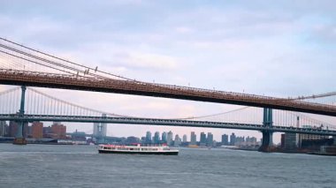 Brooklyn ve Manhattan Köprüleri East River üzerinde Circle Line botuyla. Doğu Nehri 'nden geçen iki asma köprünün ön planda bir turist feribotuyla gündüz vakti geniş açılı görüntüsü..