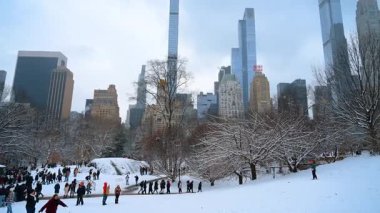 New York, ABD, 9 Şubat 2026: Central Park 'ta insanlar kızakla kayıyor ve karlı yamaçlarda yürüyor. Central Park 'ta karlı bir tepede kış manzarası var. Milyarderler arka planda gökdelenler..