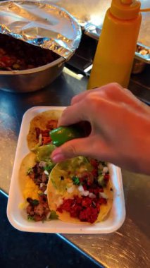 Bir tepsi taze limonu çeşitli tacoların üzerine sıkmak. Sokak yemeklerinde takolara misket limonu sıkıştıran birini yakından çek..