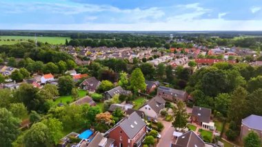 Güneş panelleri olan yeşil banliyö mahallesinin havadan bakış açısı. Bereketli bahçeleri, güneş panelleri ve uzak ormanları olan müstakil evlerin bulunduğu yerleşim bölgelerinin genel görünümü.