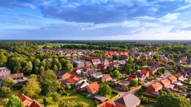 Kırmızı tuğlalı evler ve ağaçların havadan görünüşü. Kırmızı tuğla mimarisi ve mavi gökyüzünün altındaki yoğun yeşil ağaç çizgileri ile banliyö halkının panoramik insansız hava aracı görüntüleri..