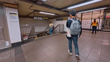 New York, ABD, 25 Ağustos 2025: Merdivenlerden metroya inen bir adamı takip etmek. Trenin gelmesini bekleyen bir sürü insanla platformda yürüyorum..