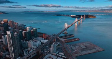 Oakland Bay Köprüsü batan güneş ışınlarıyla aydınlandı. Köprüden bir sürü araba hareket ediyor. San Francisco, California, ABD İHA 'dan.
