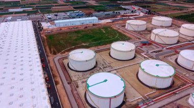 Alicante, Spain, 8 February 2026: Storage tanks and solar panel warehouse. Industrial facility featuring fuel tanks adjacent to a large warehouse with rooftop solar panels.
