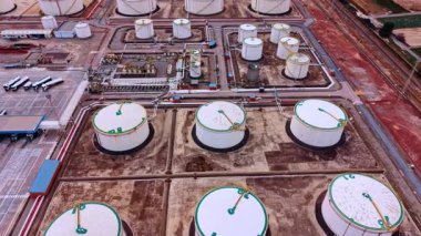 Alicante, Spain, 8 February 2026: Aerial view of industrial storage tank infrastructure. Detailed view of white storage tanks, complex piping, and industrial ground surface.
