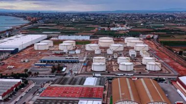 Alicante, Spain, 8 February 2026: Coastal industrial facility and tank farm. Large oil storage terminal near the sea with city skyline and road infrastructure in background.
