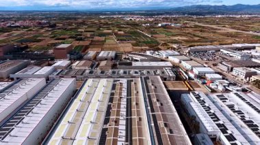 Alicante, Spain, 8 February 2026: Aerial view of industrial park and fields. Large industrial warehouses with solar panels surrounded by agricultural landscape and distant mountains.