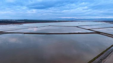 Kıyı tuzu buharlaşma havuzlarının geometrik desenleri. Deniz kıyısındaki hendeklerle su tavalarının havadan görüntüsü..