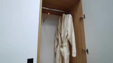 Gardıroptaki askıda beyaz bornoz var. Elektrikli çaydanlık rafta duruyor. Modern hastane odasındaki mobilyalar..