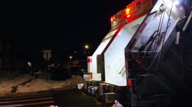 New York, ABD, 9 Şubat 2026: Karlı caddedeki çöp kamyonunun arka görüntüsü. Karlı ve tek yönlü bir tabela olan karanlık bir yerleşim yerine park edilmiş temizlik aracı..