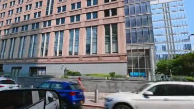 New York, ABD, 9 Ağustos 2025: Büyük taştan ofis binası ön cephesi ve geçen trafik hareketi. Ön planda sıra sıra pencereler ve bulanık arabalar olan büyük klasik bir gökdelenin dış yüzeyi..