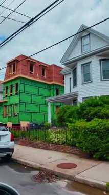 Yeşil ve kırmızı kılıflı inşaat halindeki konut binası. Su geçirmez bariyer panelleri ve ahşap çerçeve gösteren yeni ev inşaatı.