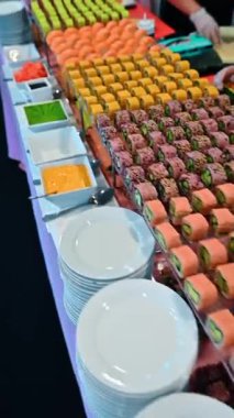 Açık büfe yemek masasında çeşitli suşi ruloları ve somon nigiri. Renkli suşi ruloları ve zencefil ve wasabi ile servis edilen somon nigiri..