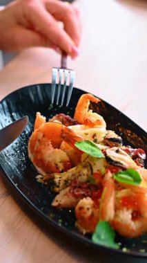 Deniz ürünleri aperatiflerini karides ve somon yumurtası ile kapatın. Pişmiş karides midyesi ve ahtapotla süslenmiş siyah tabakta kırmızı havyar..