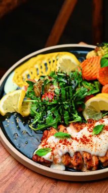 Beyaz soslu ızgara somon fileto ve tabakta kızarmış sebze. Krem soslu ızgara balık ve havuç, brokoli, karnabahar ve yeşil salata ile servis edilir..