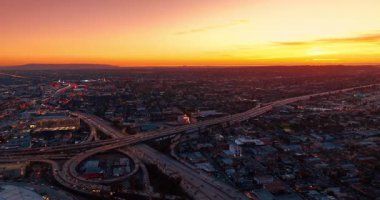 Gün batımında Los Angeles, Kaliforniya 'nın canlı döngü ve otoyollarına yaklaşıyoruz. Metropolis 'in otoyollarında hava görüntüsünden yoğun trafik var..