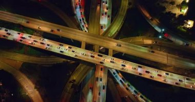 İyi aydınlatılmış çok katlı otoyollar arabalarla doludur. Geceleyin Los Angeles, Kaliforniya 'nın yoğun kavşağında yükseliyor..