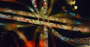 Geceleri çok katlı otoyollarla aydınlatılmış kavşak. Los Angeles, California, ABD otoyollarından yüzlerce araba geçiyor. Üst görünüm.