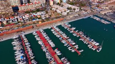 Kırmızı rıhtımları ve binaları olan sahil limanının insansız hava aracı görüntüsü. Konut bloklarının bitişiğindeki limandaki lüks teknelerin hava görüntüleri..
