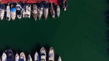 Tekneler Red Pier 'a demirlemiş. Beyaz yatların ve yelkenlilerin havadan çekilmiş fotoğrafları kırmızı ahşap iskeleye yanaştı..