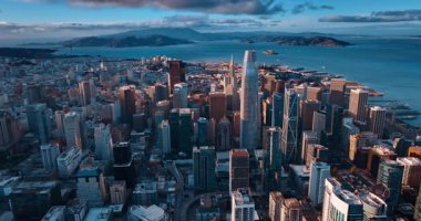 Modern metropolün yoğun şehir manzarasının görüntüleri. Batan güneş, San Francisco şehir merkezindeki gökdelenlerin tepelerini aydınlatıyor..