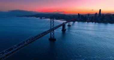 Oakland Bay Köprüsü 'ne yoğun bir trafik ile yaklaşıyoruz. Gün batımında pembe gökyüzüne karşı San Francisco silüeti.