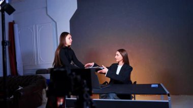 Fotoğrafçı asistanı kitabı masada oturan bir bayana veriyor. Program veya günlüğün stüdyo görüntüleri.