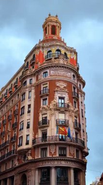 Beyaz heykeller ve kubbe ile tarihi tuğla bina süsleyin. Bulutlu gökyüzünün altında karmaşık beyaz mimari detaylara sahip çok katlı tarihi binanın dış görünüşü.