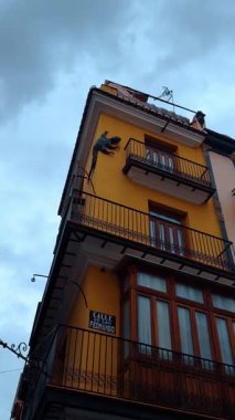 Süslü kertenkele heykeli ve balkonlu sarı bina cephesi. Metal kertenkele figürü ve siyah işlemeli demir balkonlardan oluşan sarı köşe binasının dikey çekimi..