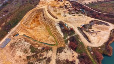 Endüstriyel makineleri ve yapay gölü olan bir kum madencisi. Taş ocağı kazma çukuru ve işleme ekipmanlarının yüksek açılı görüntüsü
