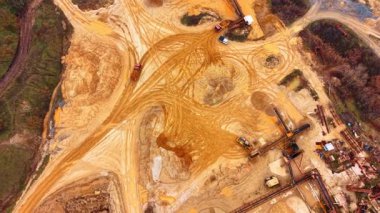 Taş ocağındaki kamyonların ve makinelerin yüksek açılı görüntüsü. Endüstriyel araç hareketinin kumlu zemindeki hava görüntüsü