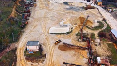 Taşıyıcı bantları ve yükleyici hava görüşlü endüstriyel kum madencilik tesisi. Taşıyıcı sistemli bir kum çukurunun yüksek açılı görüntüsü, ağır yükleyici, endüstriyel binalar ve kum yığınları.