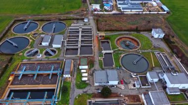 Atık su arıtma tesisinin havadan görünüşü. Bir su geri dönüşüm tesisinde dairesel netleştiriciler ve dikdörtgen havalandırma tanklarının genel perspektifi.