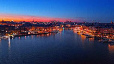 Stockholm, İsveç geceleri muhteşem ışıklarla aydınlanıyor. Nehrin üzerinden yükselen İHA görüntüleri şehre akıyor..