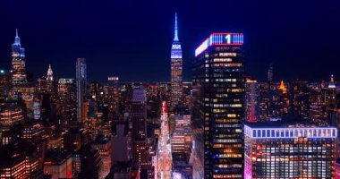 Manhattan gökdelenlerinin tepesindeki neon ışıkları. İnsansız hava aracı, şehrin çok sayıda arabayla dolu uzun ve parlak caddesine iniyor..