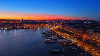 Geceleri İsveç, Stockholm 'ün muhteşem ışıkları. Nehrin üzerinde çok sayıda tekne boyunca insansız hava aracı görüntüsü..