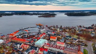 Şehrin üzerinde, manzarası parlak çatıları olan bir görüntü. Arka plandaki adaların üzerinde kara bulutlar toplandı. Hava görünümü.