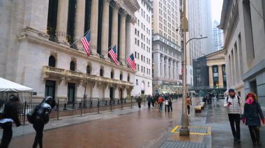 New York, ABD, 8 Şubat 2026: Ulusal bayraklarla tarihi finans binasının önünden geçen yayalar. Wall Street 'in geniş açısında borsa binası üç Amerikan bayrağıyla görünüyor.