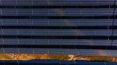 Uzun gölgeli güneş paneli sıralarının üst görüntüsü. Karanlık zemindeki fotovoltaik modüllerin doğrudan yukarıdan görüntüsü..