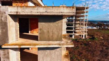 Boş pencereleri ve kapıları olan tuğla ve beton bina iskeleti. Güneşli bir günde inşaat alanında İHA görüntüleri..