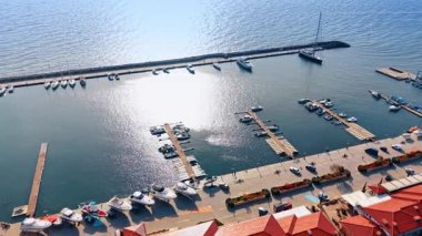 Rıhtıma ve marinaya yanaşıyoruz, rıhtımda çok tekne yok. Mavi deniz suyu parlak güneşte parıldıyor. Hava görünümü.